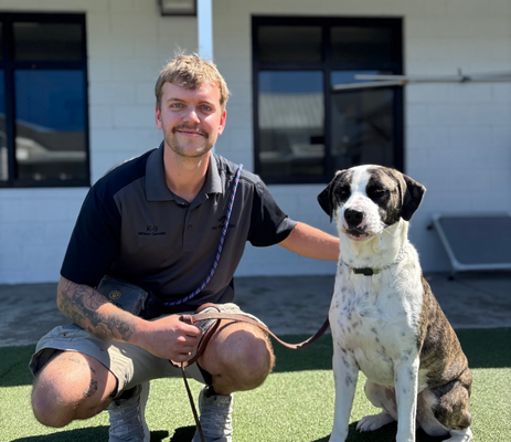 a man kneeling next to a dog