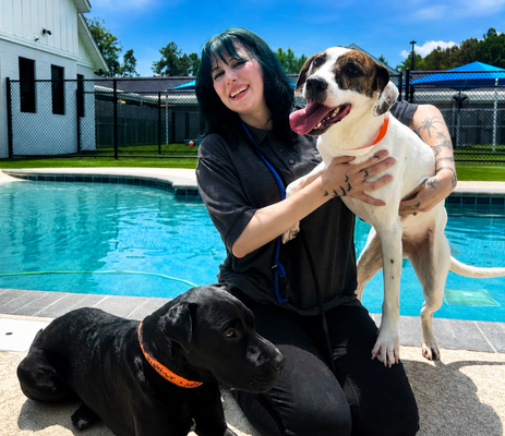 a woman holding a dog by a pool