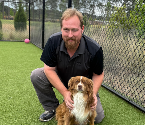 a man kneeling on grass with a dog