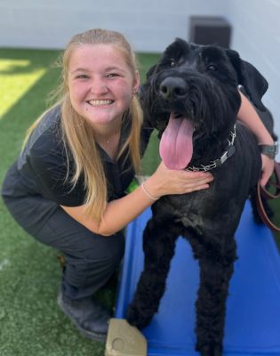 a woman petting a black dog