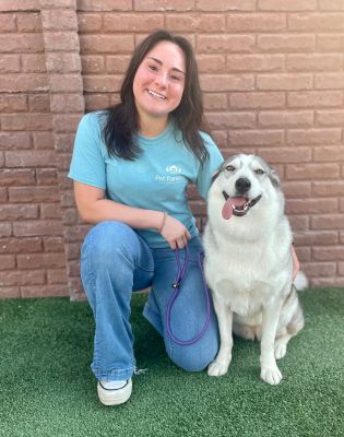 a woman sitting on grass with a dog