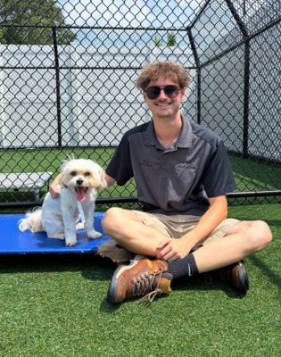 a man sitting on a blue mat with a dog on it
