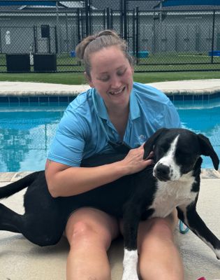 a woman sitting on a pool with a dog