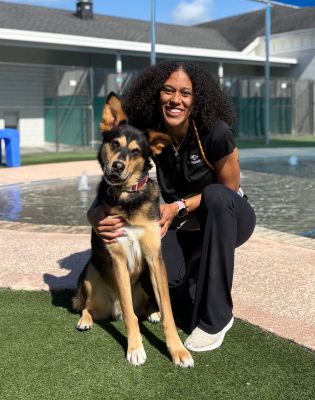 a woman kneeling on grass with a dog