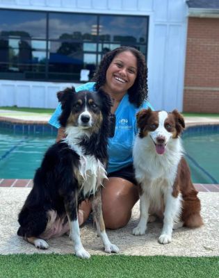 a woman sitting next to two dogs
