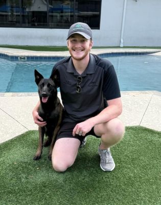 a man kneeling on grass with a dog