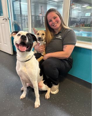 a woman sitting on the floor with two dogs