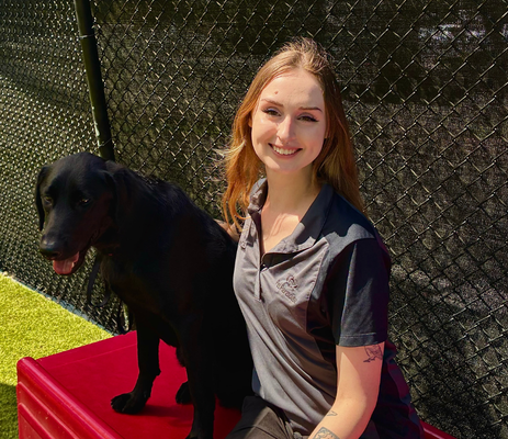 a woman sitting on a red bench with a black dog